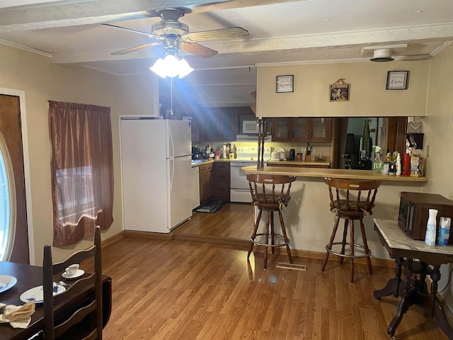 kitchen with kitchen peninsula, a breakfast bar, white appliances, crown molding, and light hardwood / wood-style flooring