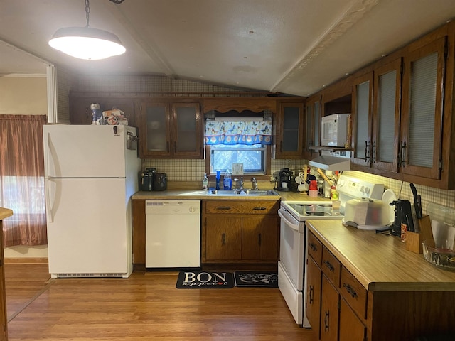 kitchen with lofted ceiling, light wood-type flooring, white appliances, and sink