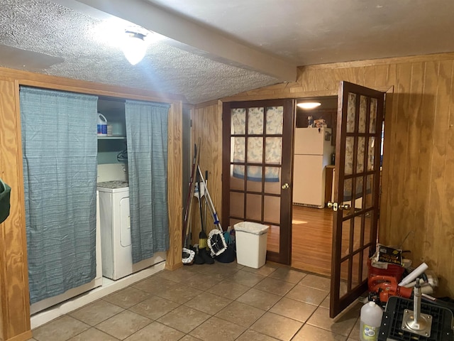 misc room featuring vaulted ceiling with beams, washer / clothes dryer, wood walls, a textured ceiling, and light tile patterned floors