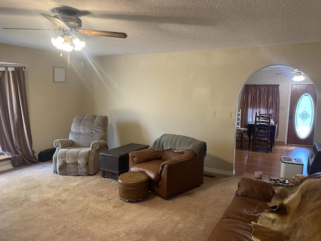 carpeted living room featuring ceiling fan and a textured ceiling