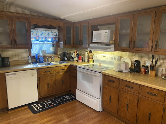 kitchen featuring white appliances, hardwood / wood-style flooring, range hood, and sink