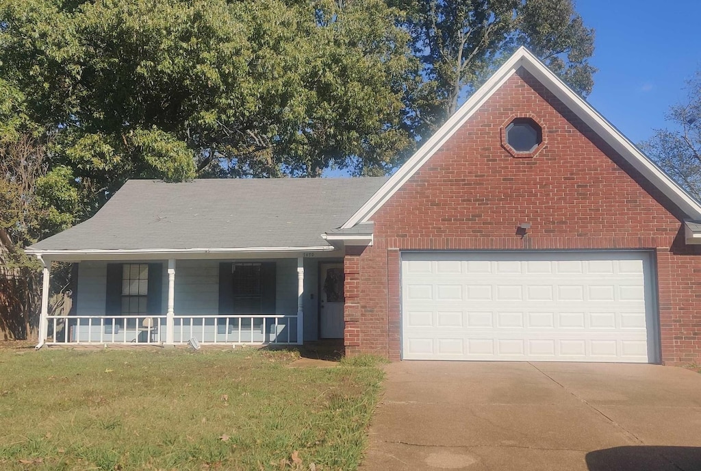 view of front of house featuring a front lawn, covered porch, and a garage