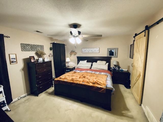 carpeted bedroom featuring ceiling fan, a barn door, and a textured ceiling