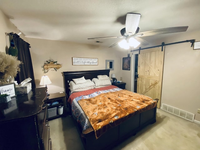 bedroom with ceiling fan, a barn door, and light colored carpet