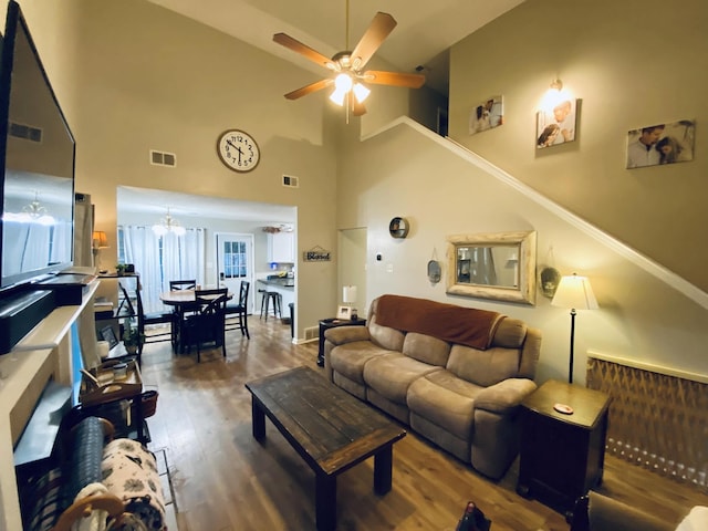 living room with ceiling fan with notable chandelier, dark hardwood / wood-style flooring, and a towering ceiling