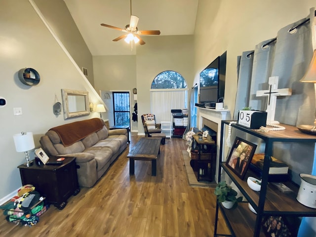 living room with ceiling fan, hardwood / wood-style floors, and a towering ceiling