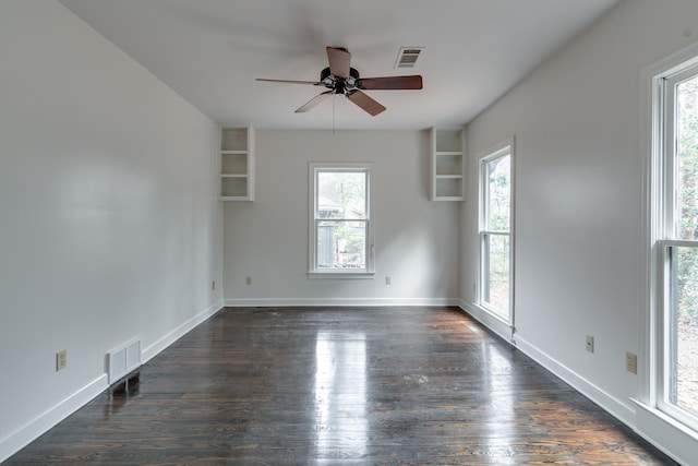 unfurnished room with ceiling fan, a healthy amount of sunlight, dark hardwood / wood-style flooring, and built in features