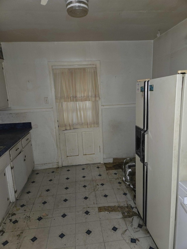 kitchen featuring white refrigerator with ice dispenser and white cabinets