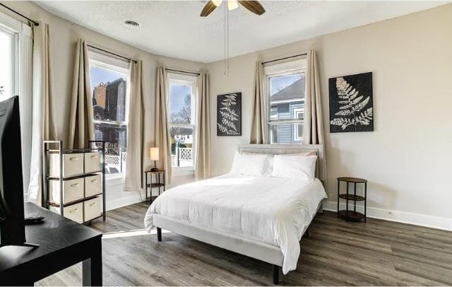 bedroom featuring dark hardwood / wood-style floors, multiple windows, and ceiling fan