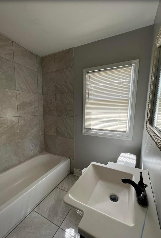 full bathroom with tile patterned flooring, toilet, a wealth of natural light, and sink