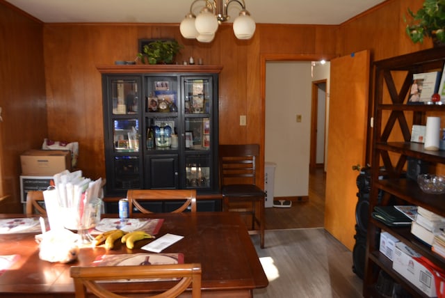 dining room featuring wood-type flooring, a notable chandelier, and wooden walls