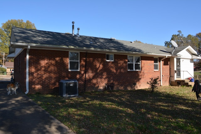 view of side of home featuring central AC unit and a yard