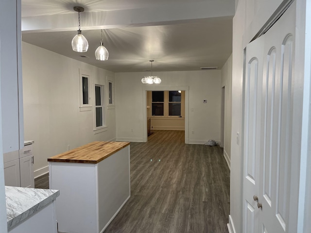 kitchen featuring wooden counters, hanging light fixtures, dark hardwood / wood-style floors, a kitchen island, and white cabinetry