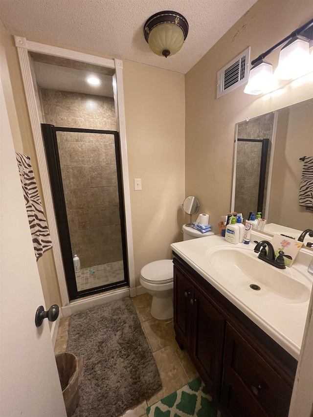 bathroom with tile patterned flooring, a textured ceiling, toilet, a shower with door, and vanity