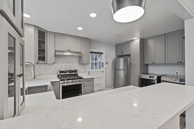 kitchen with gray cabinetry, light stone countertops, sink, and appliances with stainless steel finishes