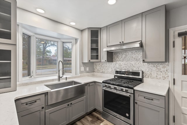 kitchen with decorative backsplash, stainless steel gas range, sink, gray cabinets, and dark hardwood / wood-style floors