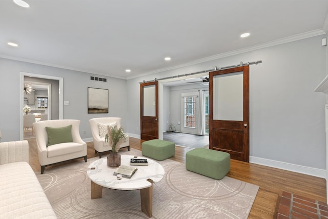 living room with hardwood / wood-style floors, a barn door, and ornamental molding