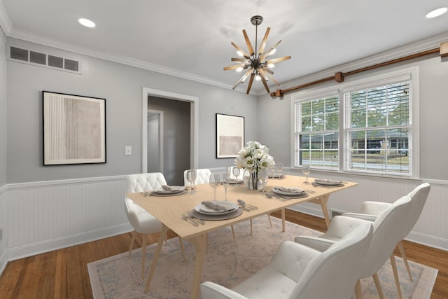 dining area with crown molding, hardwood / wood-style floors, and an inviting chandelier