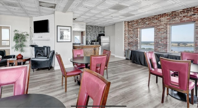 dining room featuring light wood-type flooring, a water view, and a healthy amount of sunlight