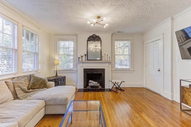 living room with a tile fireplace, a healthy amount of sunlight, a textured ceiling, and hardwood / wood-style flooring