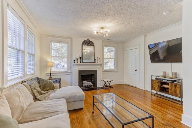 living room featuring a textured ceiling, hardwood / wood-style flooring, ornamental molding, and a tiled fireplace