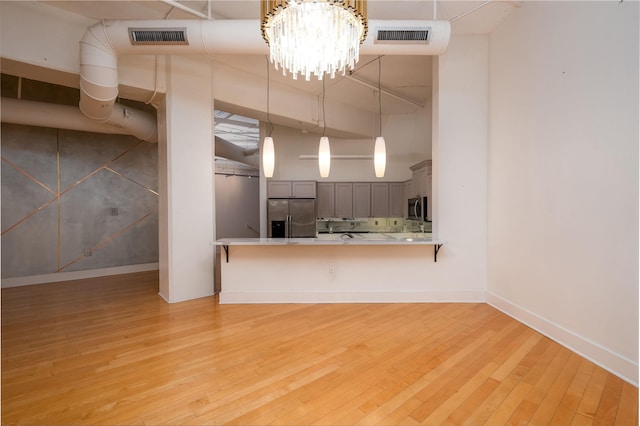 unfurnished living room featuring light hardwood / wood-style floors and an inviting chandelier