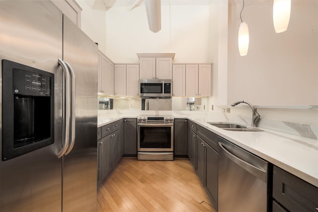 kitchen featuring pendant lighting, gray cabinetry, sink, light hardwood / wood-style flooring, and stainless steel appliances