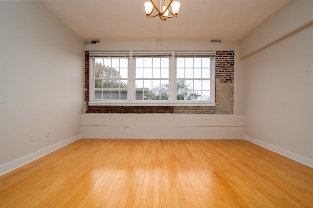 spare room featuring a chandelier and light wood-type flooring