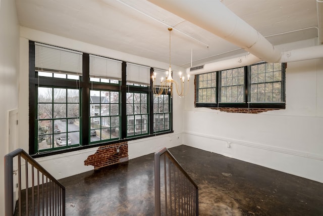 unfurnished dining area featuring a chandelier and concrete flooring