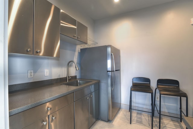 kitchen featuring dark brown cabinets, sink, and stainless steel refrigerator