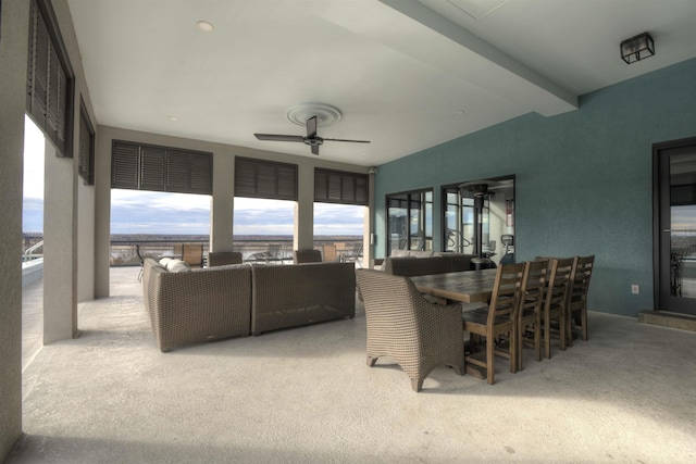 interior space with beamed ceiling, ceiling fan, and light colored carpet