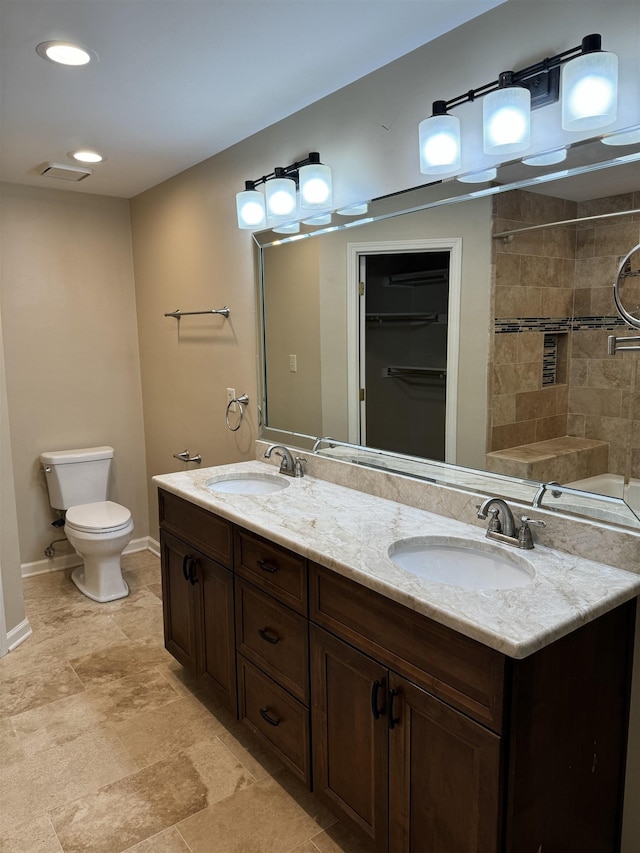 bathroom with vanity, toilet, and a tile shower