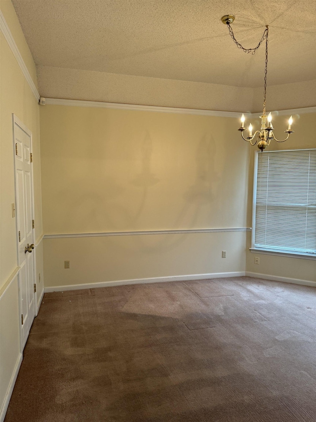 unfurnished room with dark colored carpet, ornamental molding, a textured ceiling, and an inviting chandelier