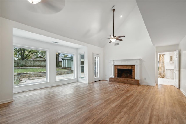 unfurnished living room with ceiling fan, a fireplace, high vaulted ceiling, and light hardwood / wood-style flooring