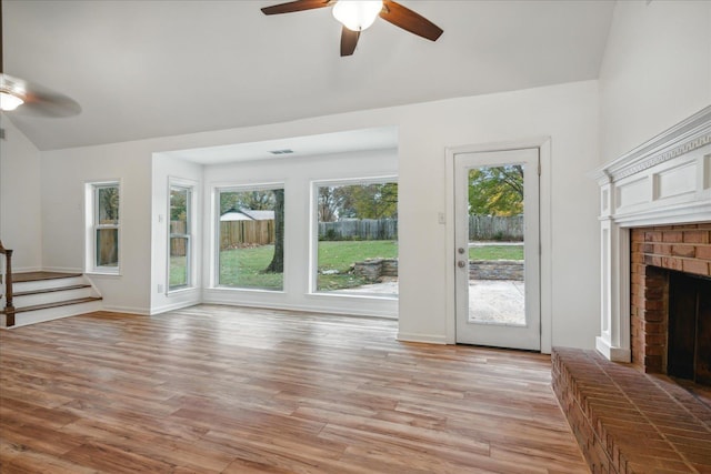 unfurnished living room with light hardwood / wood-style floors, a brick fireplace, ceiling fan, and lofted ceiling