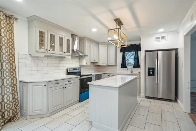 kitchen with wall chimney exhaust hood, crown molding, decorative light fixtures, a kitchen island, and appliances with stainless steel finishes