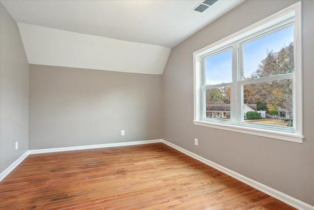 additional living space with light hardwood / wood-style floors and lofted ceiling