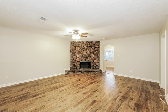 unfurnished living room featuring a fireplace, wood-type flooring, a textured ceiling, and ceiling fan