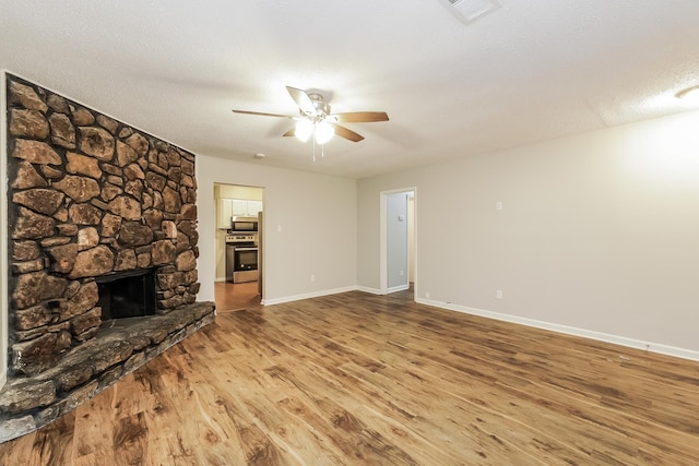 unfurnished living room featuring hardwood / wood-style floors, ceiling fan, a fireplace, and a textured ceiling