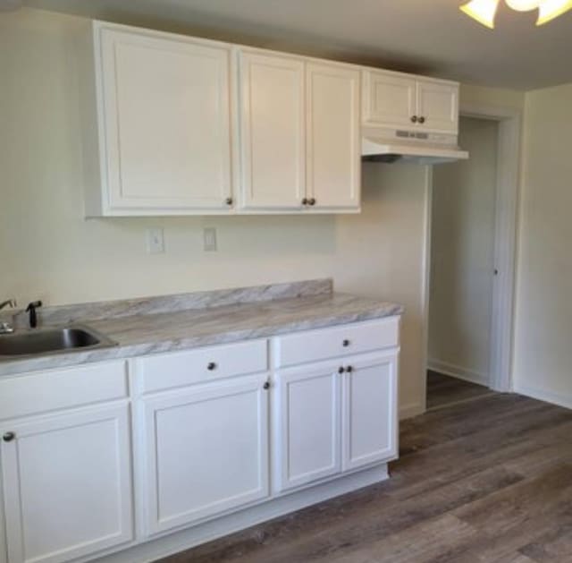 kitchen with dark hardwood / wood-style flooring, white cabinetry, and sink