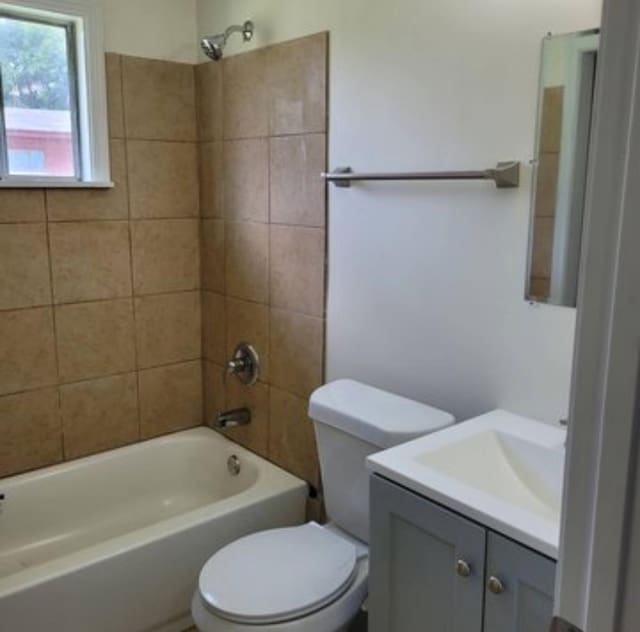 full bathroom featuring tiled shower / bath combo, toilet, and vanity