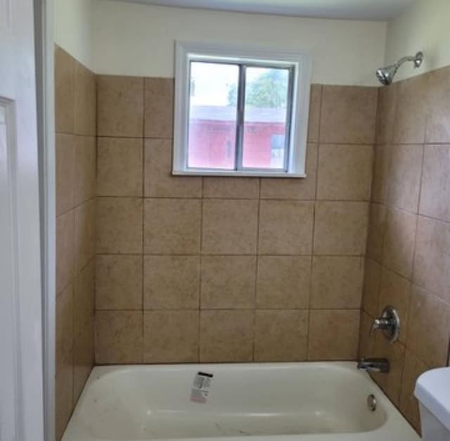 bathroom featuring tiled shower / bath and toilet