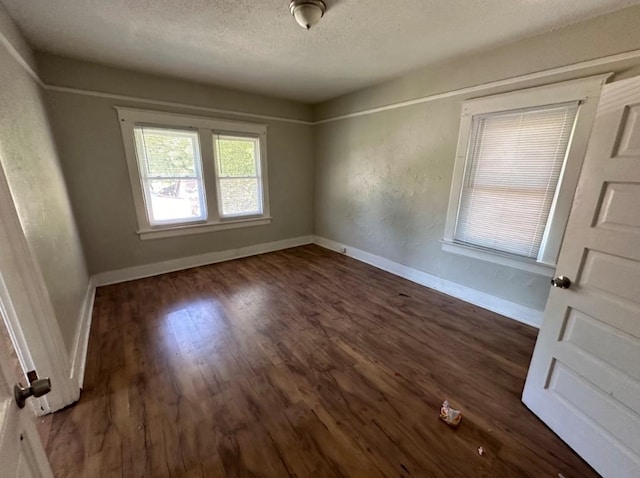 unfurnished room featuring dark hardwood / wood-style flooring and a textured ceiling