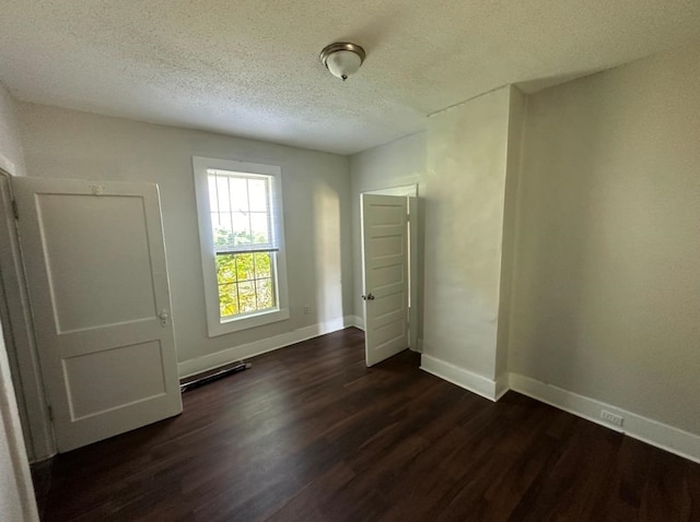 unfurnished bedroom featuring a textured ceiling and dark hardwood / wood-style floors