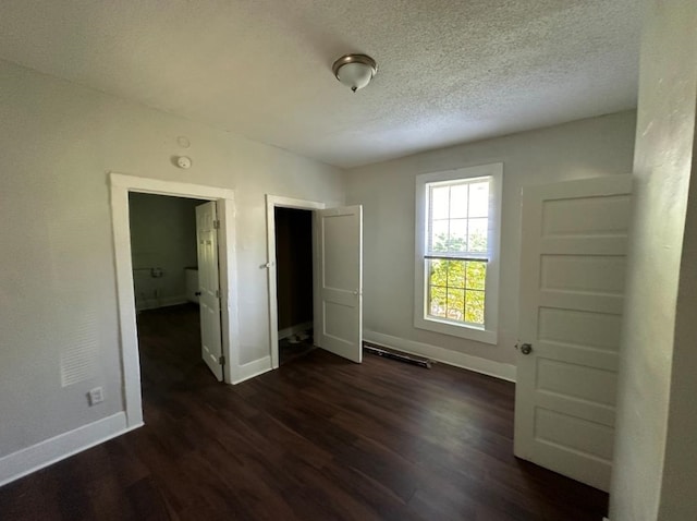 unfurnished bedroom featuring a textured ceiling and dark hardwood / wood-style flooring