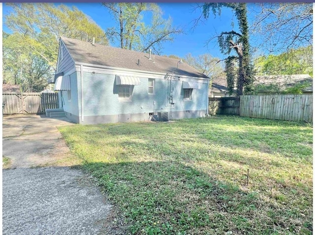 rear view of property featuring central AC unit and a lawn