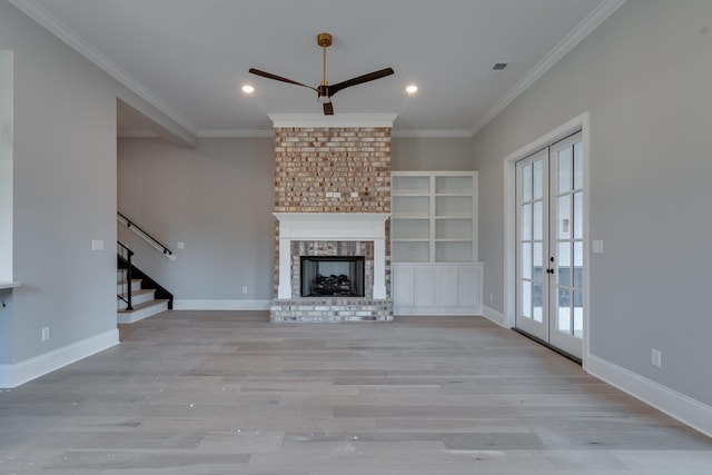 unfurnished living room with crown molding, light wood-type flooring, a fireplace, and french doors