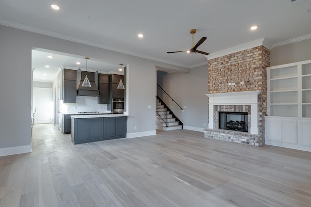 unfurnished living room with ceiling fan, a fireplace, ornamental molding, and light wood-type flooring