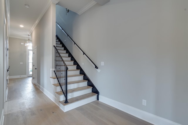 stairs featuring hardwood / wood-style floors and ornamental molding