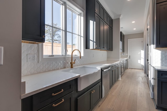 kitchen with crown molding, sink, decorative backsplash, light stone countertops, and light hardwood / wood-style floors